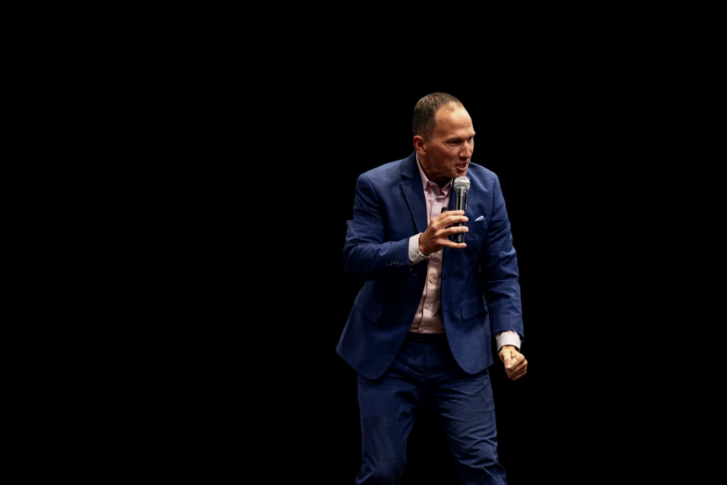 Dr. Kevin C. Snyder walking through a conference crowd with a microphone as the audience raises their hands